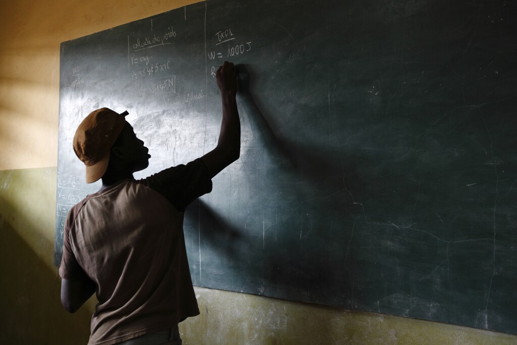 A student writes on a blackboard in a classroom at the Loyola Cultural Centre, part of the Centre Esperance Loyola (CEL - Loyola Hope Centre), a West African Jesuit organisation, in Agoe-Nyive, a suburb of Lome, April 15, 2013. The cultural centre provides education programmes to those who it believes would otherwise not have a chance to succeed in school and also because education is crucial to the struggle against HIV/AIDS. According to the African Jesuit AIDS Network, there were 120,000 people living with HIV in Togo in 2009, but HIV prevalence in the country seems to be on a downward trend. Picture taken April 15, 2013. REUTERS/Darrin Zammit Lupi (TOGO - Tags: SOCIETY HEALTH EDUCATION) - GM1E94L005E01