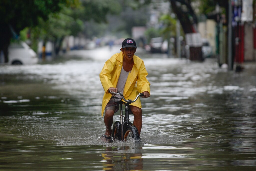 A man on a bicycle wades through a flooded street in Manila, Philippines, July 24, 2021.