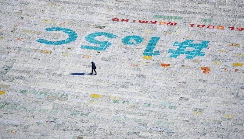 A person walks over 100,000 postcards with messages against climate change, sent by young people from all over the world and stuck together to break the Guinness World Record of the biggest postcard on the Jungfraufirn, the upper part of Europe's longest glacier, the Aletschgletscher, near Jungfraujoch, Switzerland November 16, 2018. REUTERS/Arnd Wiegmann TPX IMAGES OF THE DAY - RC1B64CAAEC0