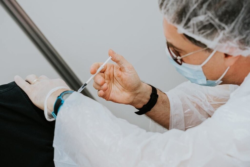 Doctor injects vaccine with surgical needle.