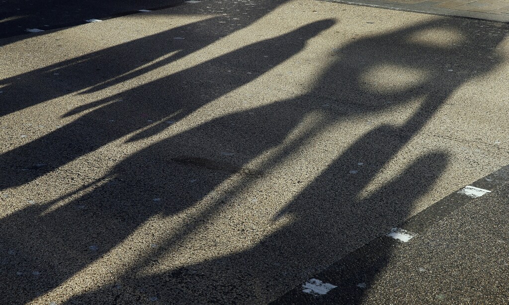 Shadows of pedestrians are cast on the street with that of a London Underground sign as they walk to a tube station in London January 13, 2015. Members of the Unite union are staging a 24-hour bus strike over pay and conditions, local media reported. REUTERS/Suzanne Plunkett (BRITAIN - Tags: TRANSPORT BUSINESS EMPLOYMENT) - LM1EB1D0WXT01