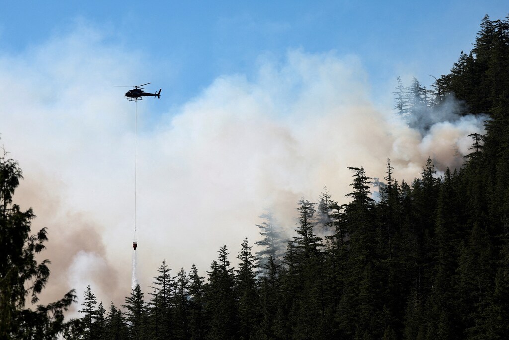 A helicopter drops water on a growing wildfire in Squamish, British Columbia, Canada June 9, 2025.