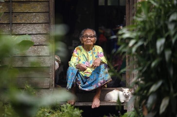 Mah Meri elder Samah Seman, 80, sits at her door with her cat in the Mah Meri tribe village of Sungai Bumbun in Pulau Carey 140 km (87 miles) southwest Kuala Lumpur March 15, 2010. REUTERS/Bazuki Muhammad (MALAYSIA - Tags: SOCIETY)