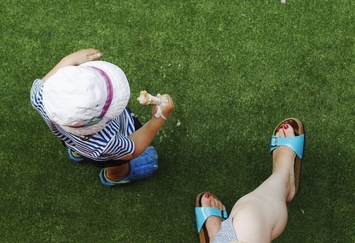 A child eats ice cream with his mother during the hot weather at the South Bank in London August 18, 2012. REUTERS/Luke MacGregor