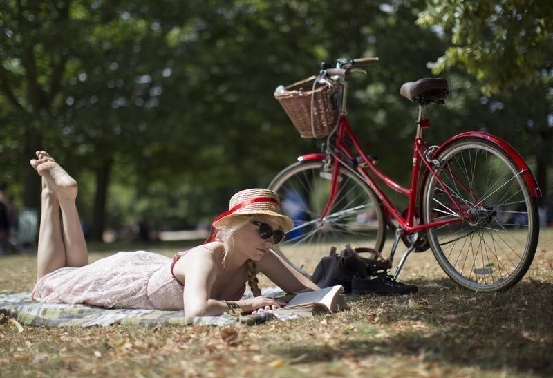 A woman reads a book on a warm day in Hyde Park in central London July 27, 2014.