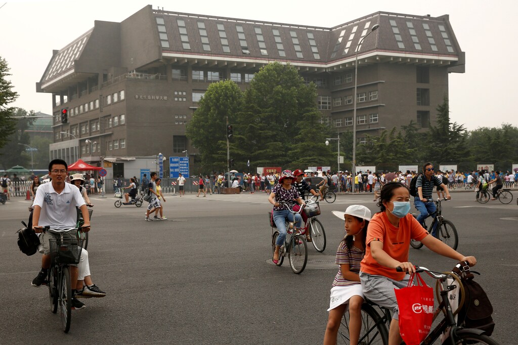 people cycle past a building in Peking University in Beijing, China