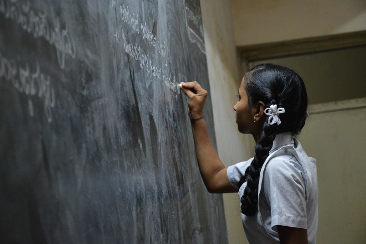 A child in India writes on a chalk board