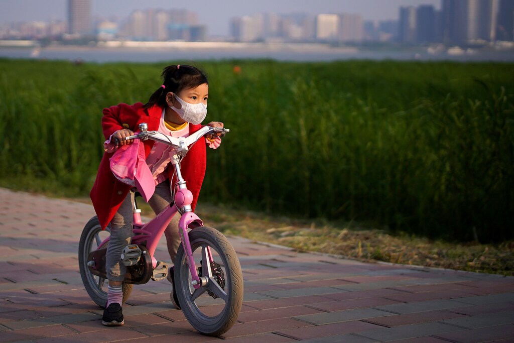 A girl wearing a face mask rides her bicycle at a park after the lockdown was lifted in Wuhan, capital of Hubei province and China's epicentre of the novel coronavirus disease (COVID-19) outbreak, April 12, 2020. REUTERS/Aly Song - RC223G9M7R84