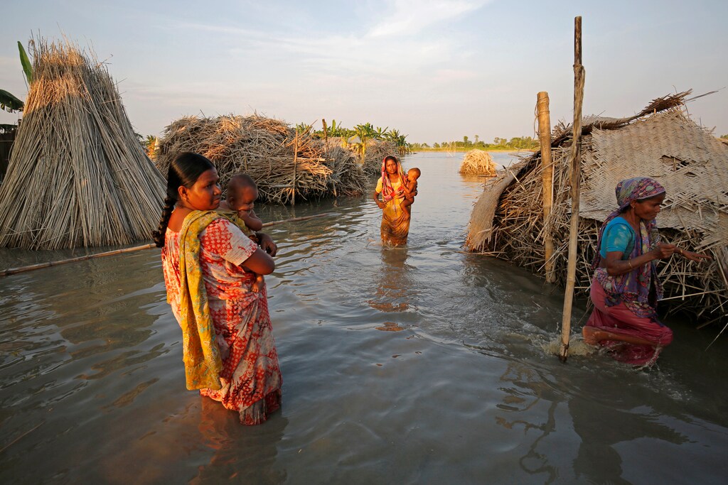 Women carry children as they make their way through a flooded area in Bogra, Bangladesh, August 20, 2017. REUTERS/Mohammad Ponir Hossain - RC129CF66CC0