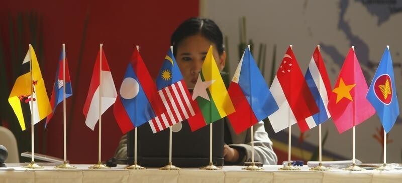 A woman sits in front of flags of the Association of South East Asian Nations (ASEAN) at Bali Nusa Dua Convention Centre in Bali November 16, 2011. Bali is hosting this year's ASEAN summit. REUTERS/Beawiharta (INDONESIA - Tags: POLITICS) - GM1E7BG0T4201