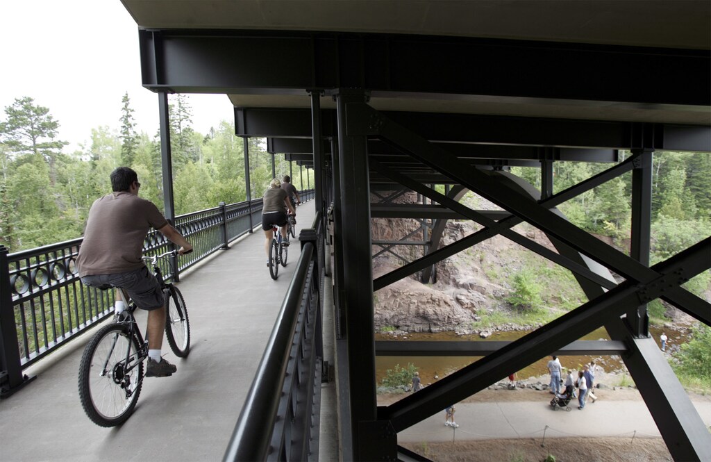 Cyclists ride on a pedestrian section below the bridge that spans the Gooseberry River, north of Duluth, Minnesota, August 5, 2007. The deck truss bridge is one of at least six that the Minnesota Department of Transportation is inspecting in wake of the collapse of the Interstate 35W bridge over the Mississippi River, August 1. REUTERS/Eric Miller (UNITED STATES) - GF1DVWDAIRAA