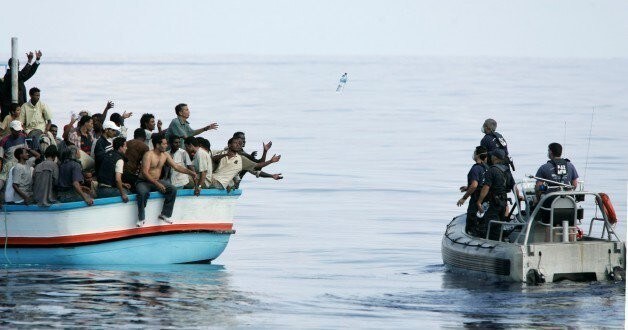 Armed Forces of Malta marines toss bottles of water to a group of around 180 illegal immigrants as a rescue operation gets underway after their vessel ran into engine trouble, some 30km (19 miles) southwest of Malta in this September 25, 2005 file photo. As many as 900 people may have died in Sunday's disaster off the coast of Libya. That would be the highest death toll in recent times among migrants, who are trafficked in the tens of thousands in rickety vessels across the Mediterranean. The mass deaths have caused shock in Europe, where a decision to scale back naval operations last year seems to have increased the risks for migrants without reducing their numbers. The European Union has proposed doubling the size of its Mediterranean search and rescue operations in response to the crisis. REUTERS/Darrin Zammit Lupi/Files MALTA OUT. NO COMMERCIAL OR EDITORIAL SALES IN MALTA TPX IMAGES OF THE DAY