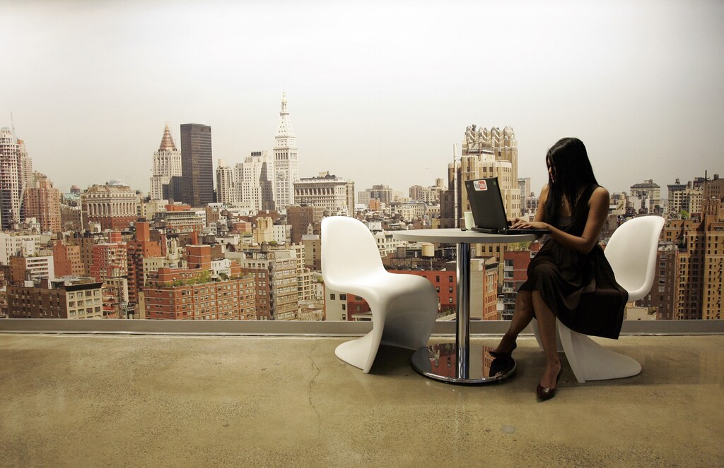 A Google employee works on a laptop in front of a mural of the New York City skyline, at the New York City company office March 10, 2008. REUTERS/Erin Siegal (UNITED STATES) - RTR1Y4YZ