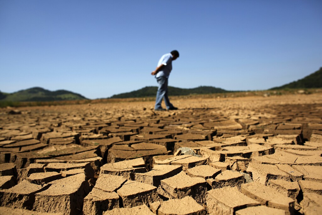 a worker of the Brazilian enterprise of Sao Paulo state, that provides water and sewage services to residential, commercial and industrial areas looks at the cracked ground of Jaguary dam in Braganca Paulista, 100 km from Sao Paulo January 31, 2014. This has been the hottest January on record in parts of Brazil, and the heat plus a severe drought has fanned fears of water shortages, crop damage, and higher electricity bills