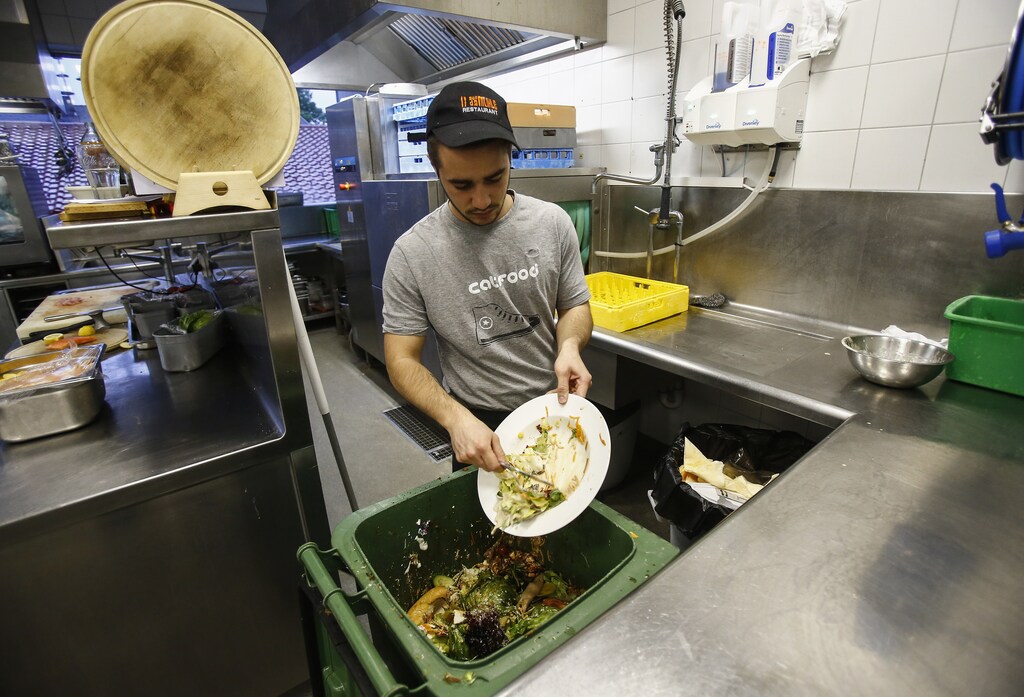 A cook throws away leftovers in the 'Auf da Muehle' restaurant in the western Austrian village of Soell June 2, 2013. Andreas Koller, the owner of the restaurant, says only about 5-10 percent of all food there is thrown away. The waste food is collected and sent weekly to a biogas plant, where it is used to help produce electricity. Cutting the amount of food that goes to waste is the special theme of this year's World Environment Day on June 5. The U.N. Food and Agriculture Organization estimates that about a third of all the food produced for human consumption worldwide every year is wasted. Picture taken June 2, 2013. REUTERS/Dominic Ebenbichler (AUSTRIA - Tags: ENVIRONMENT FOOD SOCIETY) - GM1E9650L7R01