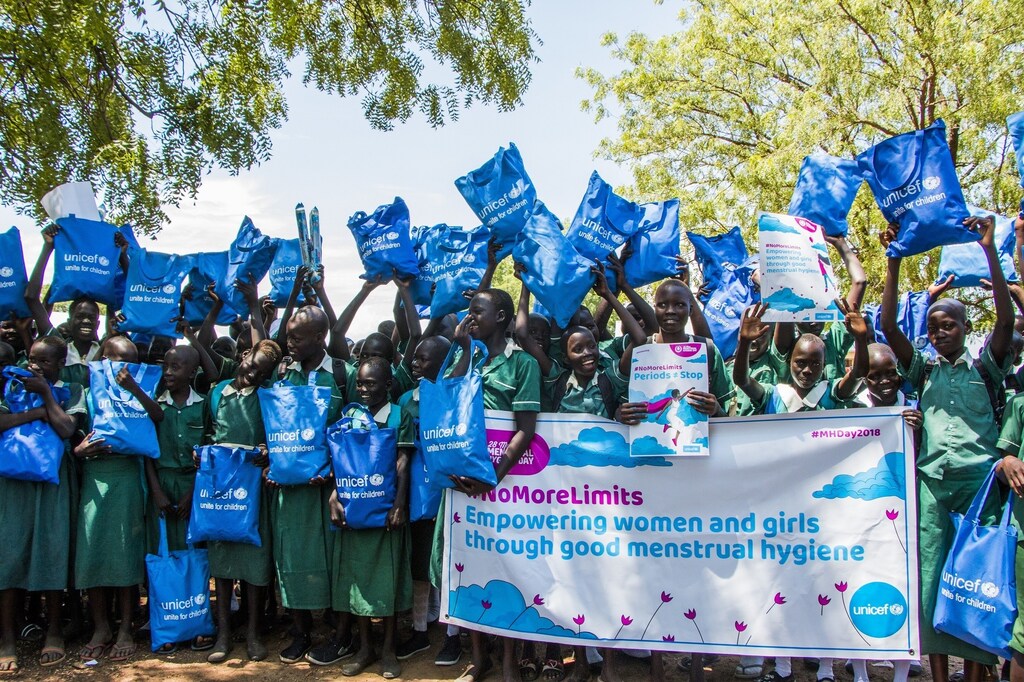 A group of children holding blue UNICEF bags in a protest about period poverty