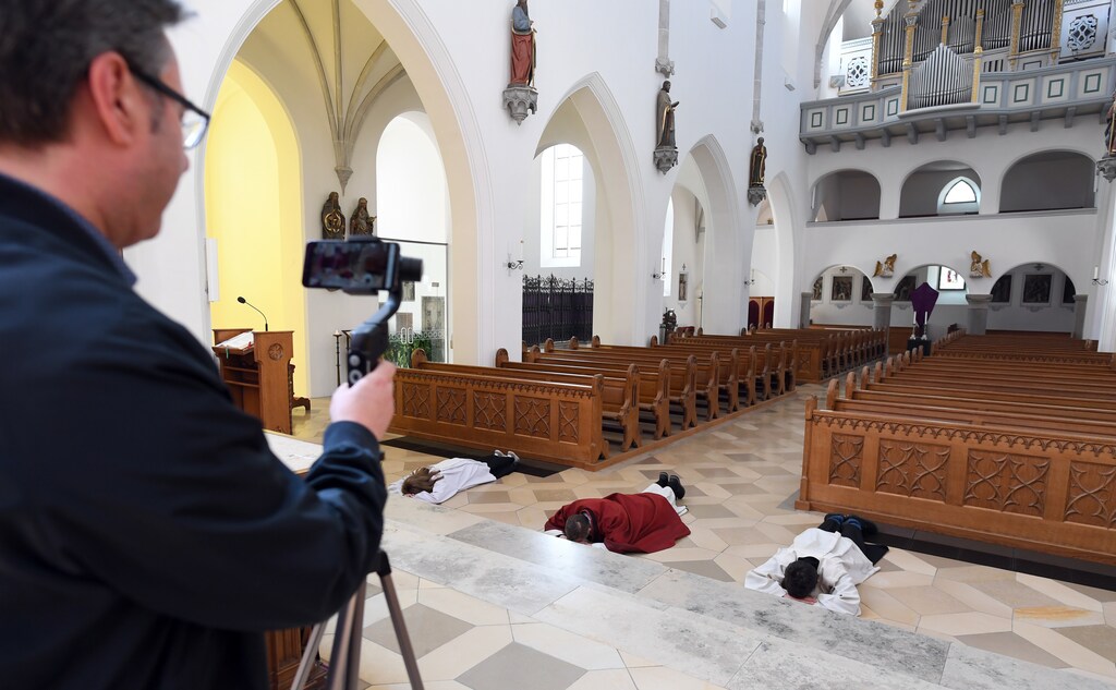A cameraman films Pastor Herbert Gugler celebrating a Good Friday liturgy, which is transmitted via internet, at the Catholic Church of the Assumption of the Virgin Mary, during the spread of the coronavirus disease (COVID-19), in Aichach, Germany, April 10, 2020.