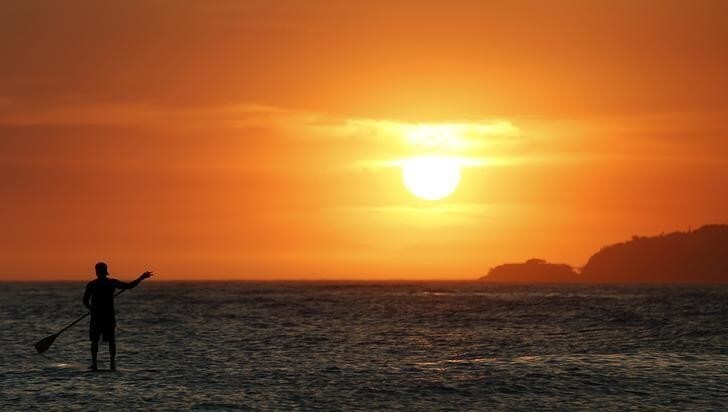 A man paddles at sunset on Arpoador beach in Rio de Janeiro, February 4, 2014. Summer temperatures for the day in Rio reached a high of 38 degrees celsius (100 Fahrenheit) according the National Meteorology Institute. REUTERS/Sergio Moraes (BRAZIL - Tags: ENVIRONMENT SOCIETY)