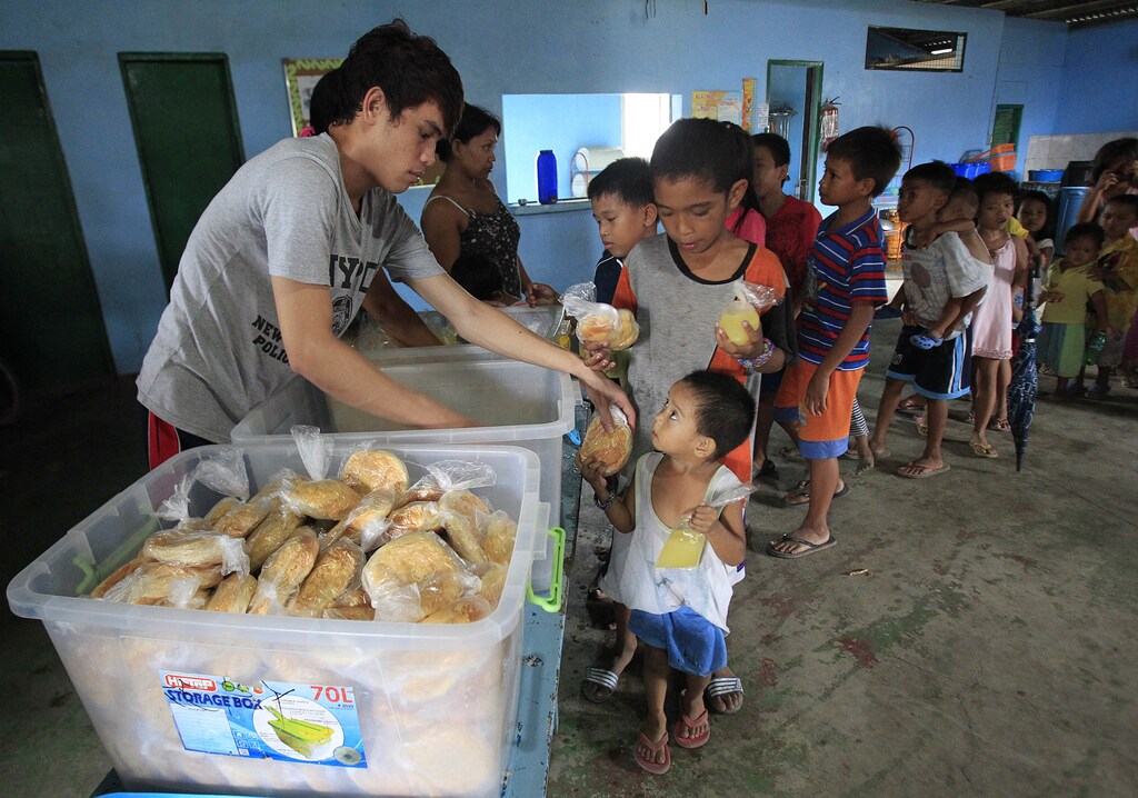 Children queue for a free meal during a feeding program by outreach group World Mission Community Care, at a slum area in the Baseco compound, metro Manila July 30, 2014. According to a poll by non-profit social research institution Social Weather Stations (SWS), the results of a nationwide survey done in late June showed that fewer families in the Philippines were going hungry in the second quarter of 2014, compared to a similar survey done in March and in 2013. According to local media, figures from the survey showed that 16.3 percent of the respondents, an estimate of 3.6 million households, said that they went hungry in the past three months. This was below March's average of 17.8 percent, an estimate of 3.9 million families, and 2013's annual average of 19.5 percent. REUTERS/Romeo Ranoco (PHILIPPINES - Tags: SOCIETY FOOD POVERTY) - GM1EA7U1BVQ01