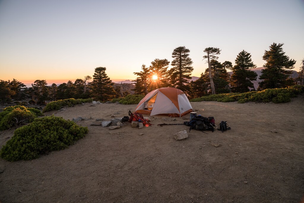 Landscape at sunset with tent and equipment in foreground.