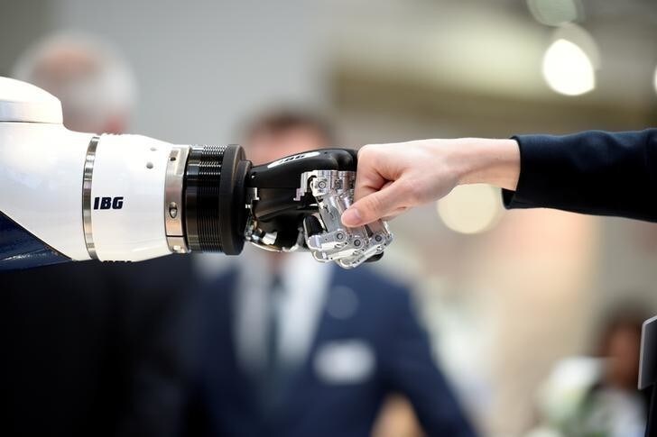 A visitor fist bumps a humanoid robot at the booth of IBG at Hannover Messe, the trade fair in Hanover, Germany, April 23, 2018. REUTERS/Fabian Bimmer