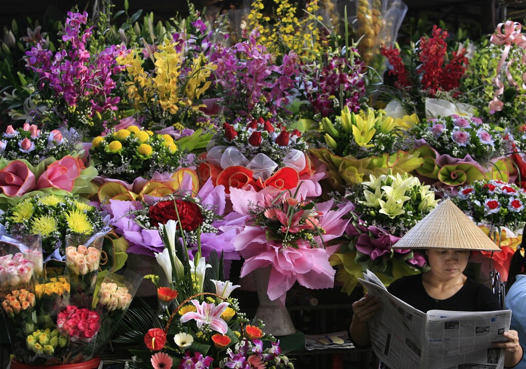 A woman reads a newspaper while selling flowers in a Hanoi market November 14, 2006.