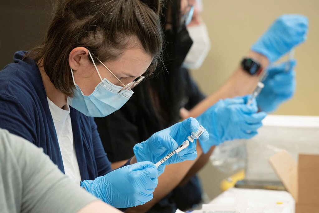 Image shows a pharmacist filling a syringe with a monkeypox vaccine.