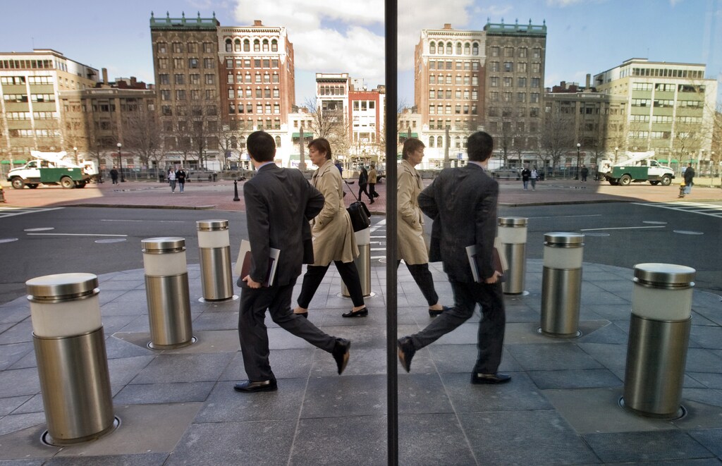 Pedestrians are reflected in the glass side of the John Hancock Tower in downtown Boston