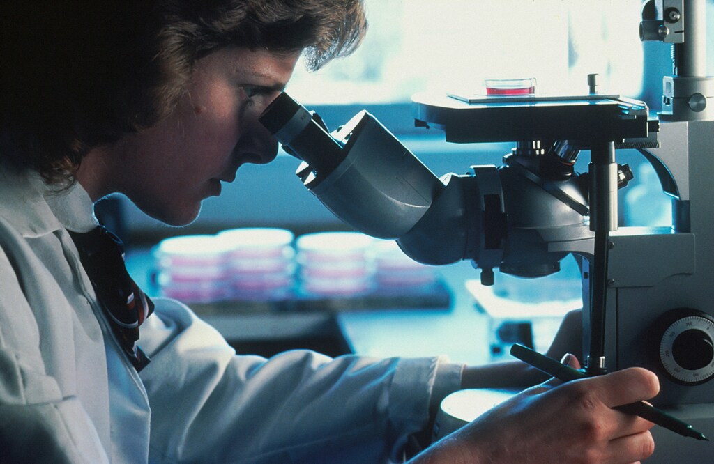 A clinician looking through a microscope, illustrating the rapid development in cancer research. Technology is helping make massive strides in cancer diagnosis and treatments.