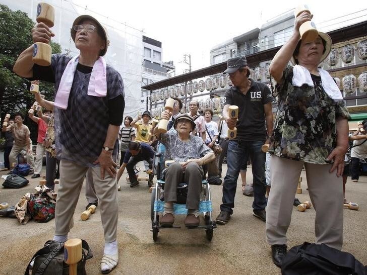 Shizue Otori, 94-year-old, exercises with wooden dumbbells, amont other elderly people, during a health promotion event to mark Japan's "Respect for the Aged Day" at a temple in Tokyo September 19, 2011. Many elderly people took part in the event held at Sugamo district, where it is known as "Harajuku for Grannies." REUTERS/Yuriko Nakao (JAPAN - Tags: HEALTH SOCIETY)