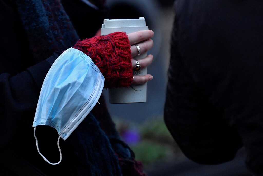 A woman has her mask on her wrist as she drinks coffee as the coronavirus disease (COVID-19) restrictions begin to ease, in Dublin, Ireland January 22, 2022. REUTERS/Clodagh Kilcoyne