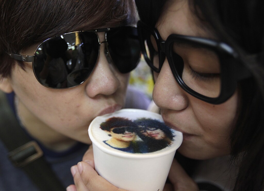 A couple drinks a cup of latte with their picture printed on top of the milk foam at a Family Mart in Taipei August 13, 2013. As part of Qixi Festival celebrations, customers of Family Mart's Let's Cafe were given the complimentary service of getting their pictures printed with edible inks on their lattes, according to a Family Mart employee. Qixi, also known as the Double Seventh Festival and the Chinese version of Valentine's Day, falls on the seventh day of the seventh month in the Chinese lunar calendar. REUTERS/Pichi Chuang (TAIWAN - Tags: ANNIVERSARY SOCIETY TPX IMAGES OF THE DAY) - GM1E98D17GF01