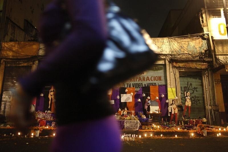 A passer-by walks past a Day of the Dead altar built by sex workers at a red light district in Mexico City October 31, 2013. Sex workers built the altar to remember their deceased colleagues, especially those who were violently murdered in the last few years. The annual Day of the Dead is observed on November 1 and 2. REUTERS/Edgard Garrido (MEXICO - Tags: RELIGION SOCIETY) - GM1E9B1148W01