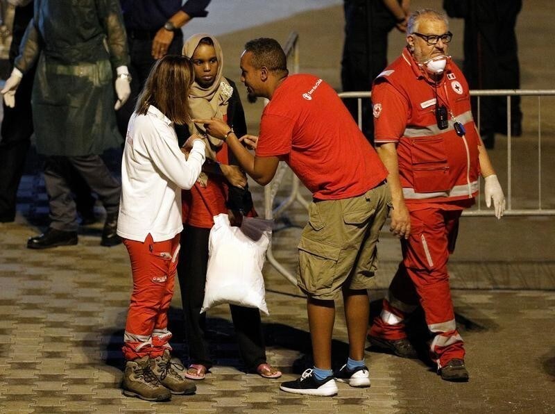 An unaccompanied minor migrant is helped as she disembarks from the Italian coast guard vessel "Diciotti" at the port of Catania, Italy, August 22, 2018.