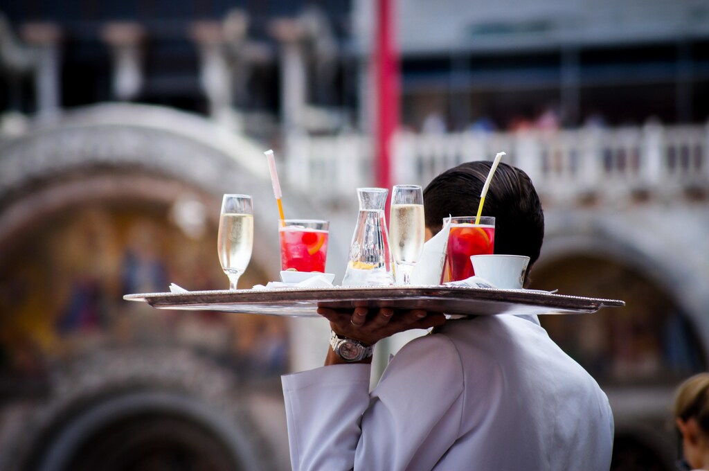 A waiter carrying drinks at a restaurant.