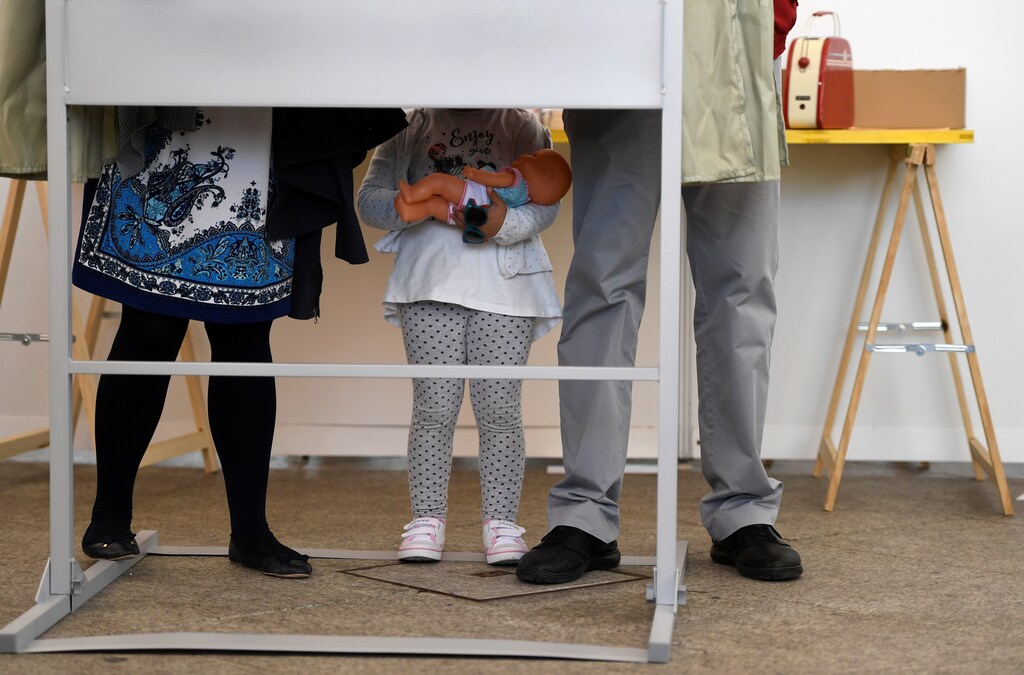 A girl and her parents are seen in one of the booths before voting during Spain's general election in Pola de Siero, April 28, 2019. REUTERS/Eloy Alonso - RC1749582090