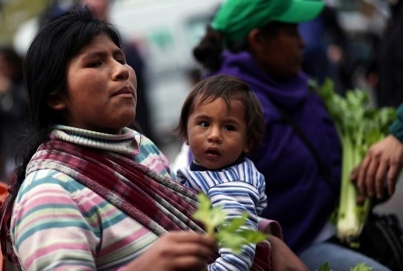 A vegetable grower carries a child as she arrives to Plaza de Mayo square to hand out products as a way of protesting price distortions and double-digit inflation they say crushes profits, in Buenos Aires, Argentina September 14, 2016.