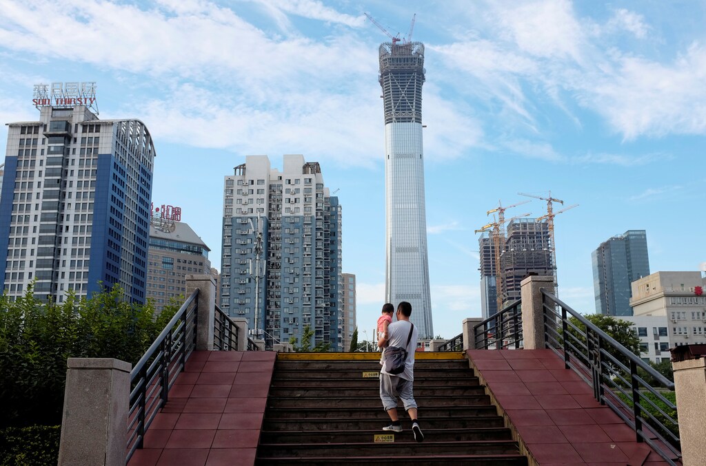 A man carrying a girl walks through a bridge at a park next to Beijing's central business area, China August 29, 2017. REUTERS/Jason Lee - RC1B3D140F40