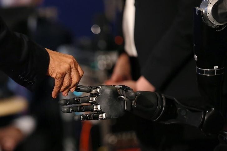 U.S. President Barack Obama touches a robotic arm operated by Nathan Copeland, a quadriplegic brain implant patient who can experience the sensation of touch and control a remote robotic arm with his brain during a tour of the innovation projects at the White House Frontiers conference in Pittsburgh, U.S. October 13, 2016. REUTERS/Carlos Barria