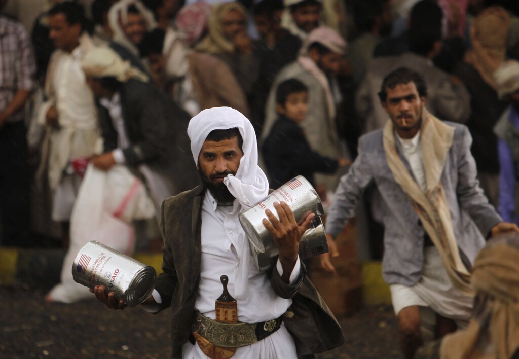 A Yemeni refugee carries cooking oil he received at a relief center in Sanaa