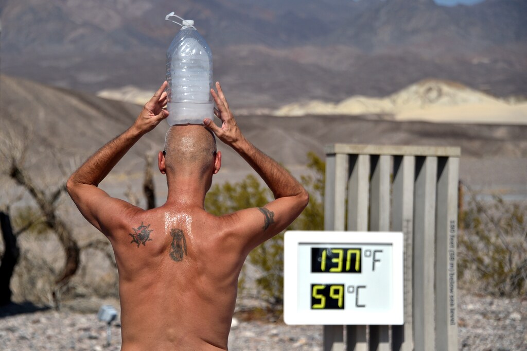Steve Krofchik of Las Vegas keeps cool with a bottle of ice on his head as the unofficial thermometer reads 130 degrees Fahrenheit (54.4 Celsius), with a mechanical fault on the display which causes the numbers to render incorrectly, at the Furnace Creek Visitors Center in Death Valley, California, U.S. August 17, 2020. REUTERS/David Becker TPX IMAGES OF THE DAY - RC20GI9I0D6I