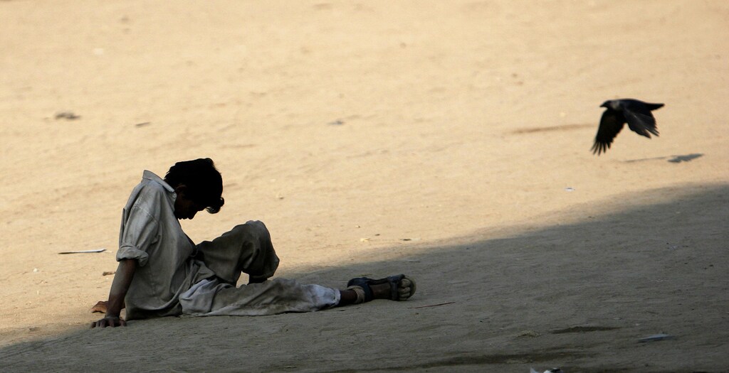 An unemployed migrant worker sits on a ground in Mumbai November 24, 2008. Thousands of migrants, mostly from north India, come to Mumbai every year seeking casual labour. Due to the lack of employment and low wages, alcoholism, drug abuse and quarrels over money sharing is rampant among the migrants, who usually end up being homeless