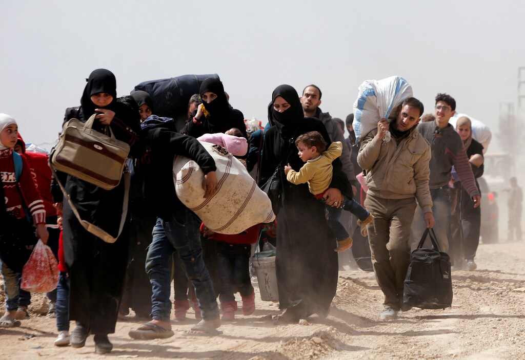 People walk with their belongings as they flee the rebel-held town of Hammouriyeh, in the village of Beit Sawa, eastern Ghouta, Syria