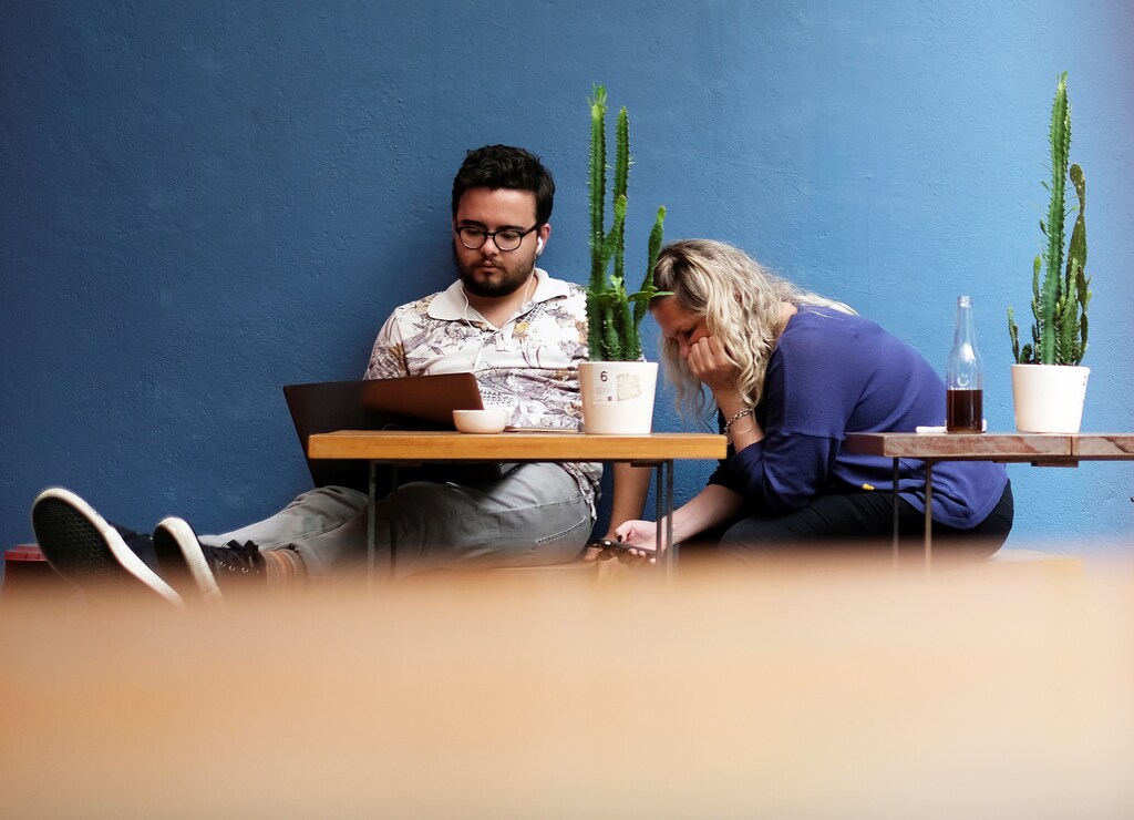 A man uses his computer next to a woman writing a message on her mobile phone at a cafe in Sao Paulo, Brazil October 17, 2017. REUTERS/Nacho Doce - RC1F35182670