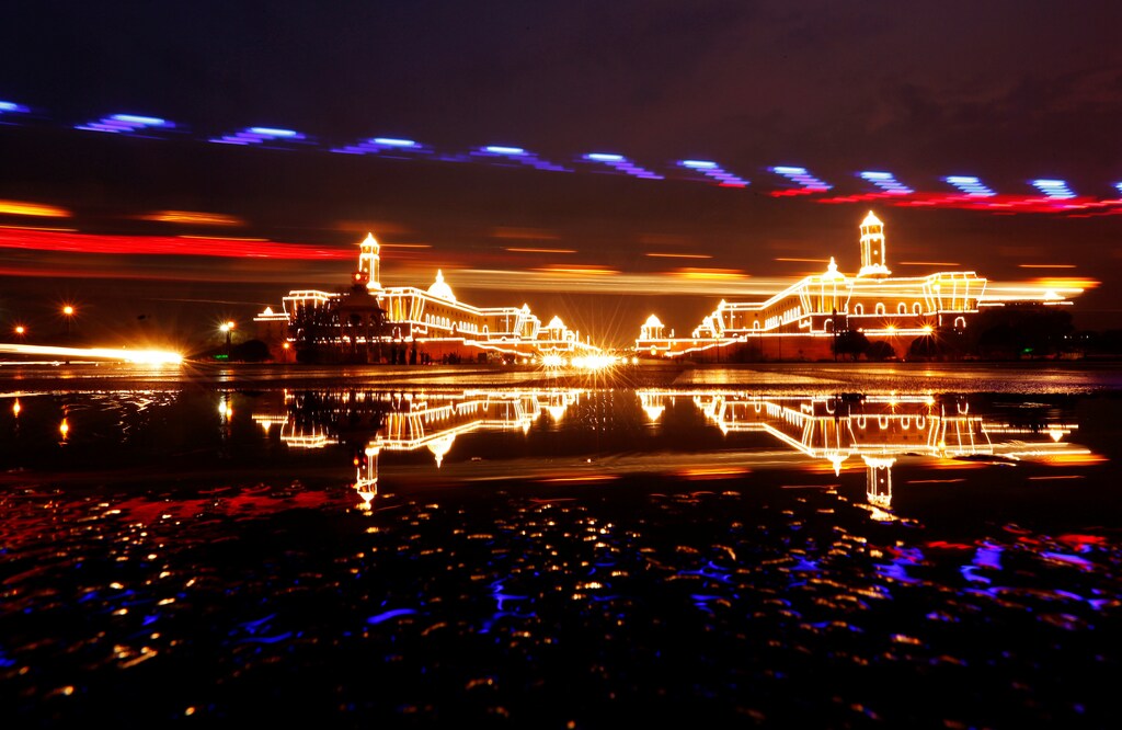 A police car drives past the Illuminated Indian Defence Ministry (L), Presidential Palace (C) and Home Ministry ahead of Indias Independence Day celebrations in New Delhi, India, August 13, 2016. Picture taken with long exposure. REUTERS/Adnan Abidi - S1AETVFPPDAC
