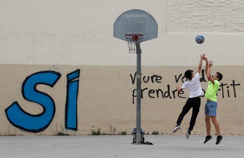 Youths play basketball in front of pro-independence graffiti, three days after the banned independence referendum in Barcelona, Spain October 4, 2017. REUTERS/Yves Herman - RC19BFF14870