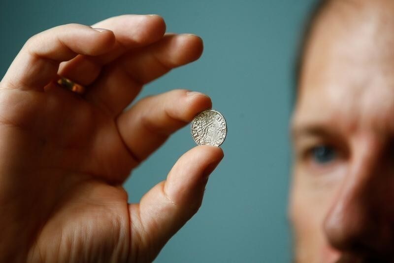 A museum employee poses with a coin from a collection of 1000-year-old recently discovered coins, from the Harold II and William I period, now on display at the British Museum in London, Britain, August 28, 2019. REUTERS/ Henry Nicholls - RC17D3B4B4D0