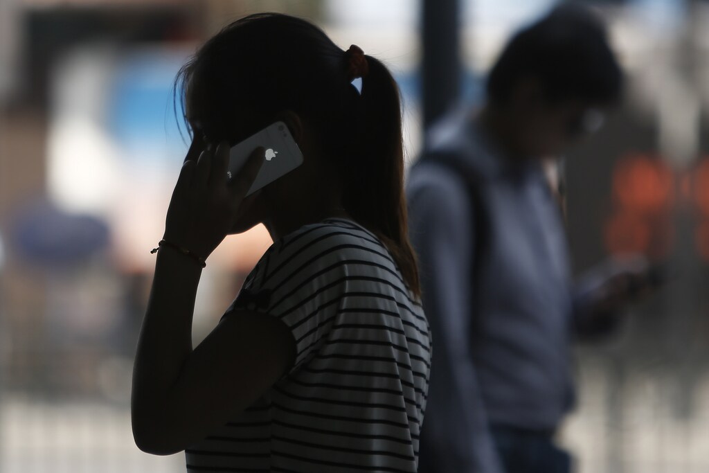 A woman speaks on her iPhone as she walks on a busy street in downtown Shanghai September 10, 2013. Apple Inc is expected to introduce a cheaper version of the iPhone on Tuesday, bringing one of the industry's costliest smartphones within reach of the masses in poorer emerging markets. The world's most valuable technology company, which many expect to unveil an iPhone 5C in several colors alongside the latest high-end iPhone 5S, is trying to beat back rivals like Samsung Electronics Co Ltd and Huawei Technologies Co Ltd in markets like India and China, where it is fast losing ground. REUTERS/Aly Song (CHINA - Tags: BUSINESS SCIENCE TECHNOLOGY) - RTX13FHJ
