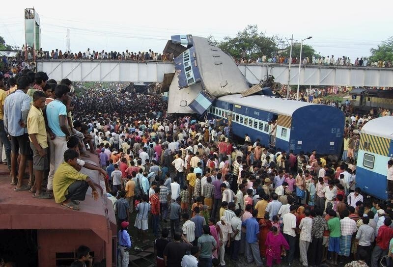 Onlookers stand at the site of a train accident at Sainthia in the eastern Indian state of West Bengal July 19, 2010. A speeding passenger train crashed into another waiting at a station in eastern India early on Monday, killing at least 60 people in India's second major accident in as many months, officials said. REUTERS/Stringer (INDIA - Tags: TRANSPORT DISASTER IMAGES OF THE DAY) - GM1E67J1F3L01