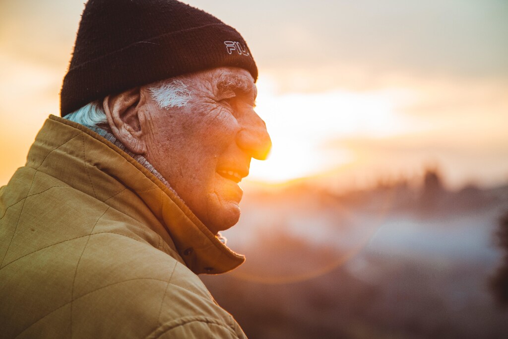 Older man sitting at sunset.